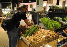 Aardappelen scheppen. De houten kratten geven de supermarkt een natuurlijke uitstraling. Bij de aardappelen zijn bijpassende kruiden geplaatst.