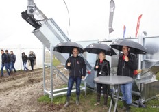 In de regen met paraplu: Pieter Flikweert, Agnes van Dijke en Marco Geense voor een hun machine van Van Dijke Groep.