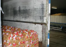 Op de achtergrond is een vrachtwagen te zien die zojuist aardappelen heeft afgeleverd. Deze vrachtwagen met verpakte aardappelen staat klaar om zometeen te vertrekken.