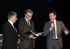 Gaston Opdekamp en Dirk van de Plas overhandigen het eerste exemplaar van het boek over 75 jaar Veiling Hoogstraten aan Kris Peeters.